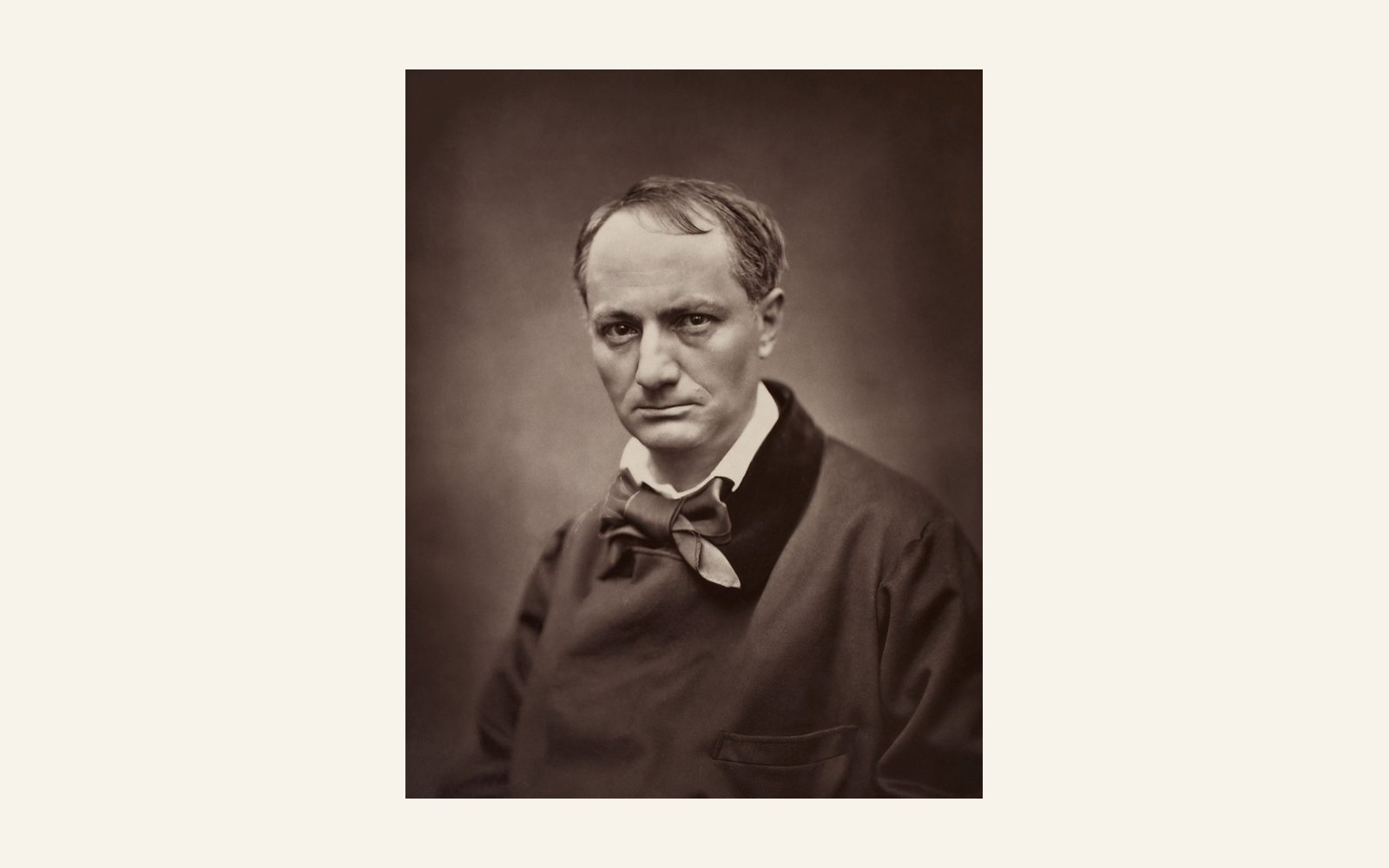 A black-and-white photograph of Charles Baudelaire, head and shoulders, in a dark coat and white shirt with a loose tie. His hair is receding and he looks straight at the camera with a serious face.