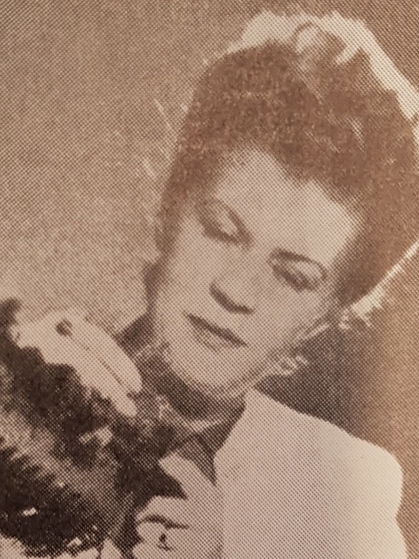 Black-and-white halftone portrait of Astrid Sampe, a woman with dark hair swept up, looking down at a dark patterned fabric she holds in her hands.