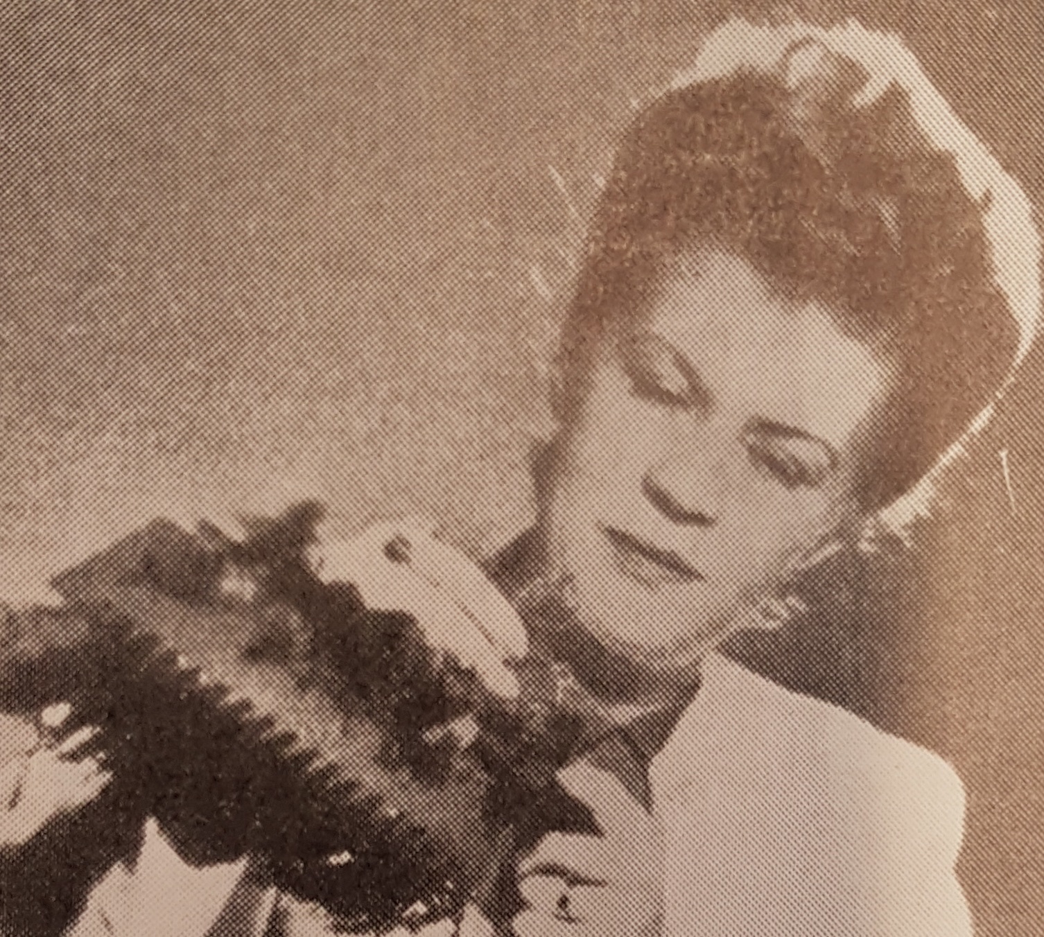 Black-and-white halftone portrait of Astrid Sampe, a woman with dark hair swept up, looking down at a dark patterned fabric she holds in her hands.